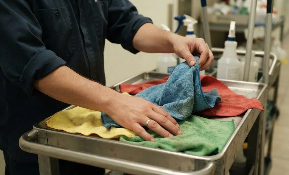 Professional cleaning technician using a color-coded microfiber cloth to ensure cross-contamination prevention.